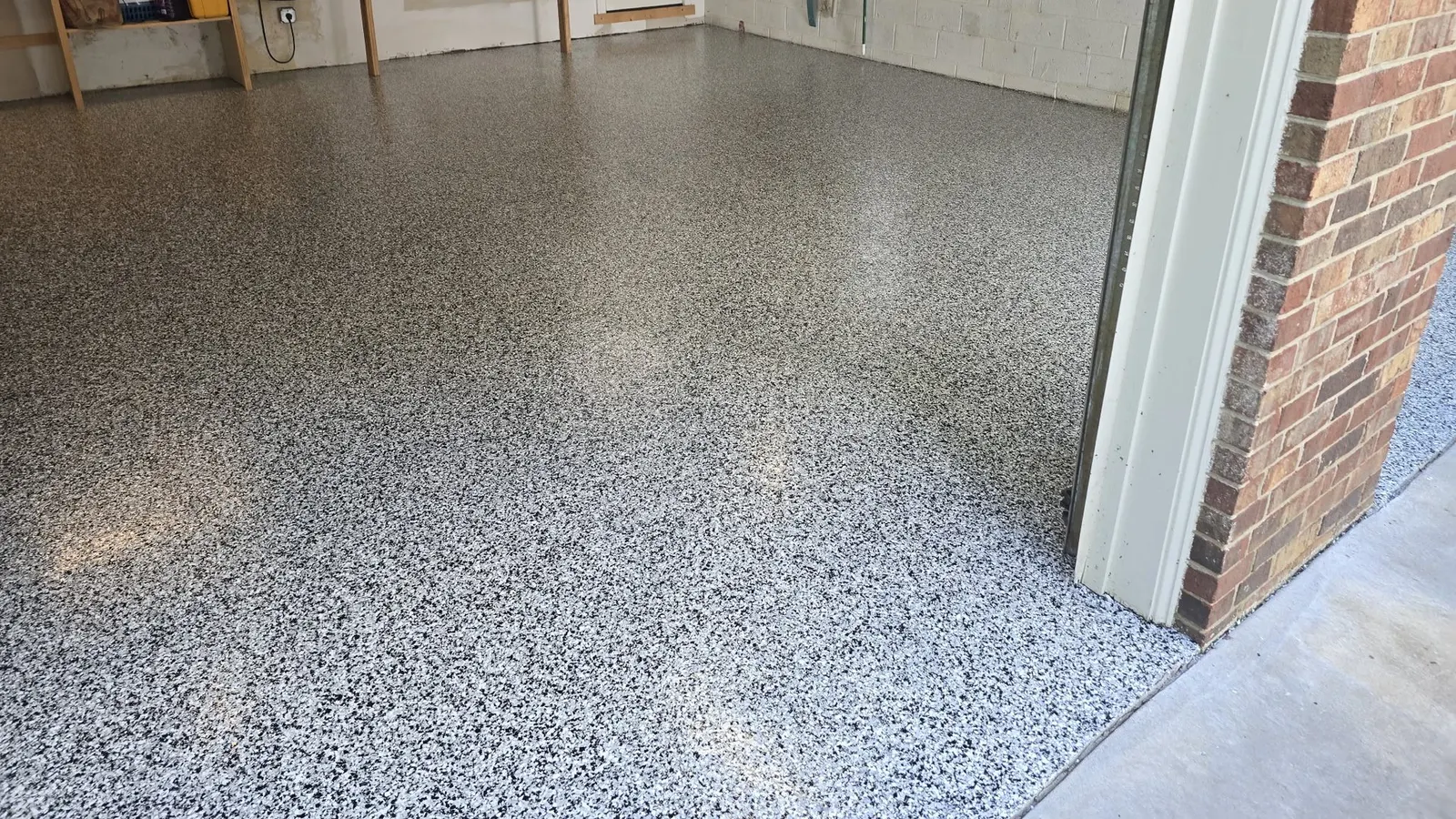 Finished gray and white polyaspartic flake floor filling a clean two-car garage up to the door threshold