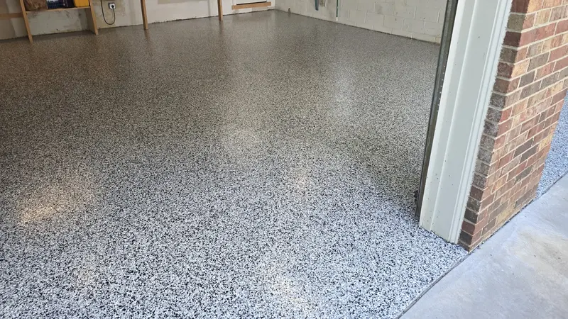 Finished gray and white polyaspartic flake floor filling a clean two-car garage up to the door threshold