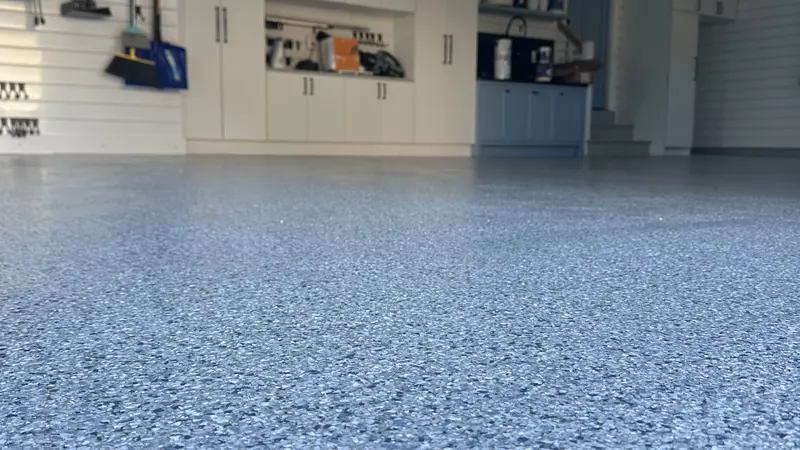 Blue-gray polyaspartic flake floor filling a clean residential garage with white storage cabinets